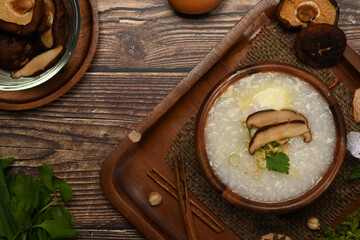 Fototapeta na wymiar Traditional Chinese rice porridge with shiitake mushroom, soft boiled egg, slice ginger and slice scallion topping on wooden table