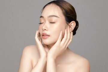 Beautiful young Asian woman model with perfect clean fresh skin on grey background. Face care,...