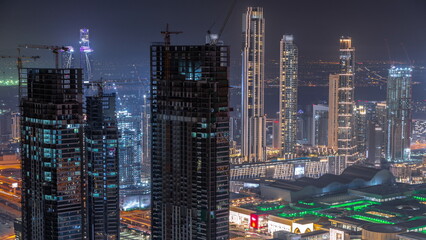 Fototapeta na wymiar Dubai downtown with large-scale construction of a residential complex with cranes aerial night timelapse