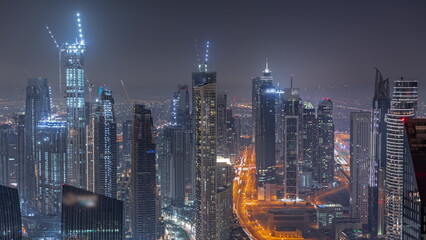 Downtown skyline with modern architecture form above night timelapse. Aerial view of Dubai business bay towers.