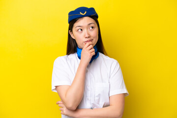 Airplane Chinese woman stewardess isolated on yellow background having doubts and with confuse face expression