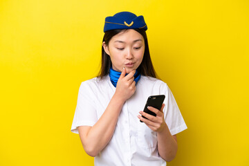 Airplane Chinese woman stewardess isolated on yellow background thinking and sending a message