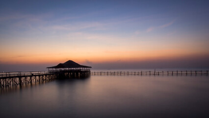 Fototapeta na wymiar Sunrise on the beach of East Surabaya, Indonesia with traditional house called joglo