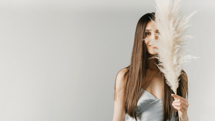 Portrait of a beautiful girl with long hair with a bouquet of pampas grass on her face. Beauty...