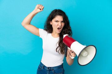 Teenager Russian girl isolated on blue background shouting through a megaphone to announce something