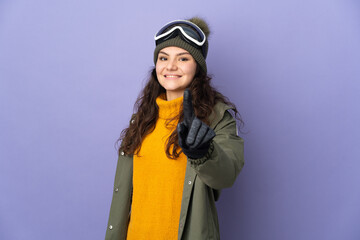 Teenager Russian girl with snowboarding glasses isolated on purple background showing and lifting a finger