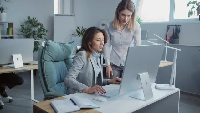 Boss speaking with worker woman discussing use laptop computer In modern office . On background people working. Portrait. Close up