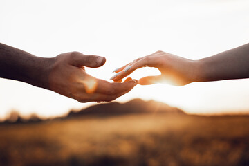 Young married couple touches each other's hands. Photo of hands on sky background. Photo with light noise