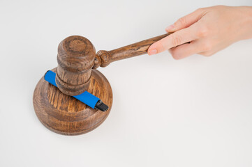 Judge hammering disposable vape with referee's gavel on white table. 