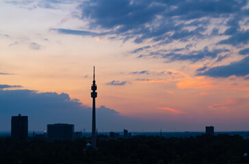 Skyline panorama of Dortmund Germany with TV-Tower and city centre skyline after colorful Sunset summer. Blue hour twilight with silhouettes of buildings, factories and power plants on the horizon. - obrazy, fototapety, plakaty