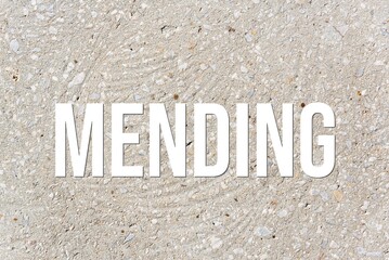 MENDING - word on concrete background. Cement floor, wall.