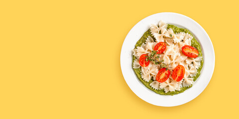 Paste with tomatoes and spinach sauce in a plate on yellow background. Copy space. Top view