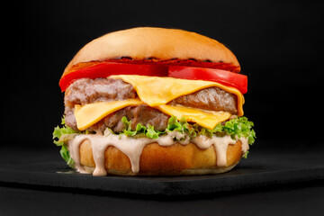 Beef burger with cheese and salad on a black background