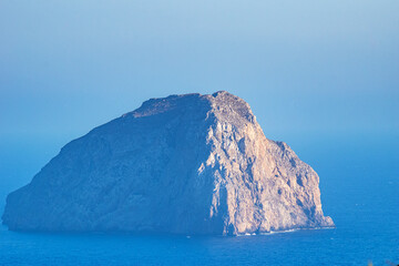 The magical islet of Hytra or else Avgo (Egg) close to Kapsali, Kythera idland. The steep and rocky inhospitable territory is decorated by the yellowish semprevivum, and is also a nesting falcon place