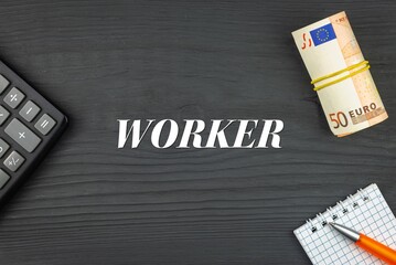 WORKER - word (text) and euro money on a wooden background, calculator, pen and notepad. Business concept (copy space).