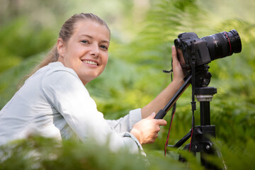 beautiful smiling girl using camera on tripod in the countryside