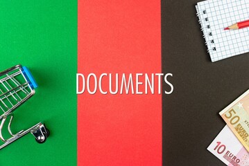 DOCUMENTS - word (text) and euro money on a table of different colors, a trolley, a basket of grocery notepad and a red pencil. Business concept, buying, selling, supermarket, store (copy space).