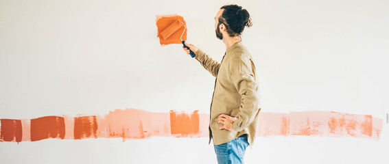 Man painting wall. Man with paint roller painting wall. Repair and house renovation concept.