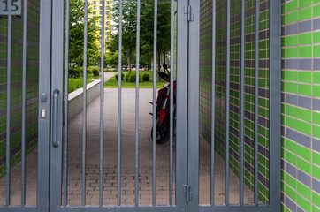 The motorcycle stands behind a steel gate