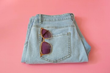 Blue jeans on a pink table. Pop art style. Women's, teenage daily comfortable clothes. The concept of thrifty shopping, second-hand.