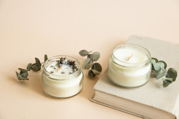 Two candmade candles from paraffin and soy wax in glass with wooden wick and dry herbal isolated on...