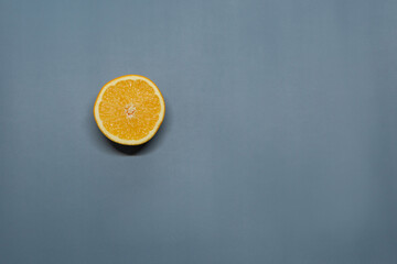 A ripe orange cut in half lies on a blue background