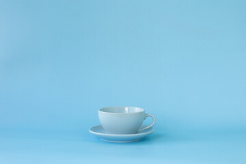 Blue cup and saucer on a blue background side view.