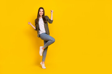 Fototapeta na wymiar Full body photo of ecstatic overjoyed lady raise fists in victory win money in lottery giveaway isolated on yellow color background