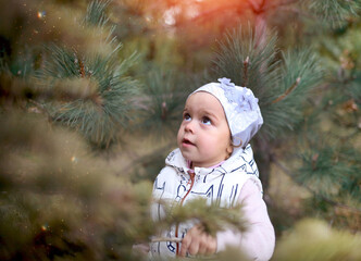 Little cute Caucasian girl in a white vest and cap playing in the autumn pine forest. Nature background. Childhood and joy concept. Copy space on the left