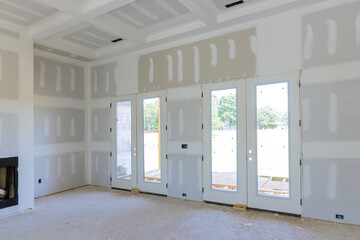 In preparation for painting a newly constructed house, finishing putty is being applied to the walls of an empty apartment