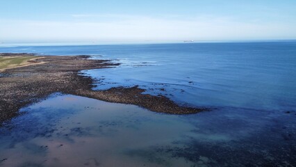Aerial view of the incredible coastline of Scotland with views of the North Sea. Blue sky background with ocean waves. 