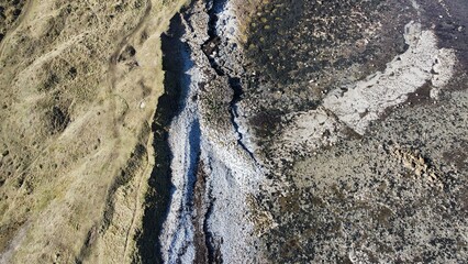 Aerial view looking straight down onto a rocky coastline with waves crashing. Taken in Dunbar Scotland. 