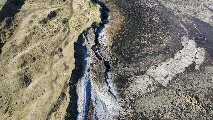 Aerial view looking straight down onto a rocky coastline with waves crashing. Taken in Dunbar Scotland. 