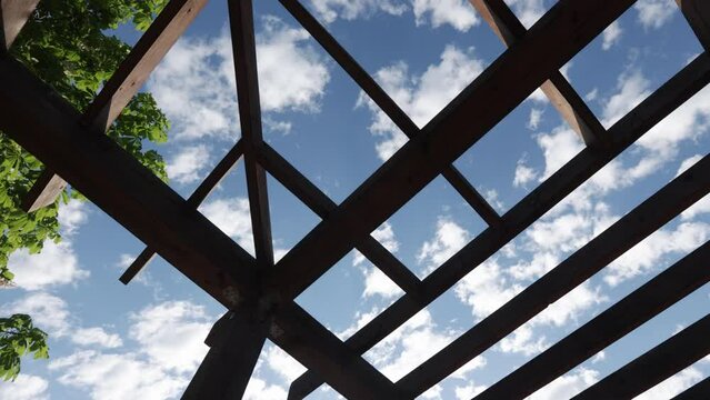 Wooden pergola in a city recreation park with a lake in the residential area