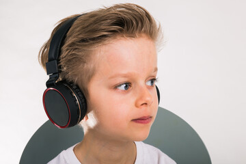 Beautiful kid boy in big headphones. A boy in a white  t-shirt listening to music. copy space