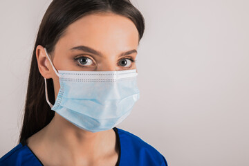 portrait of young female doctor in medical mask looking at camera.