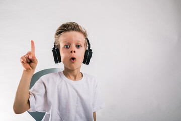 Little small happy boy 6-7 years old wearing white t-shirt headphones listen to music sing song in...