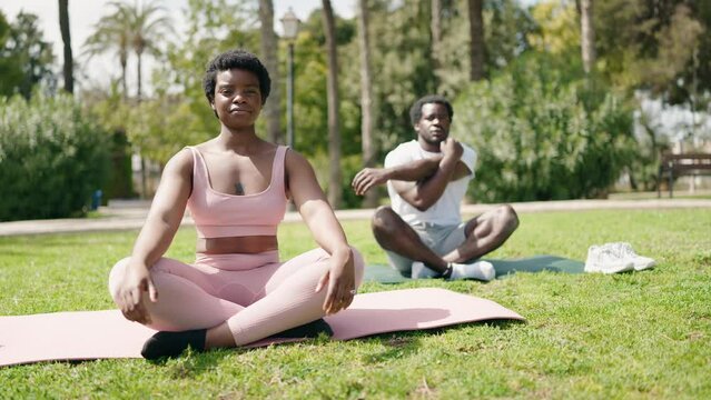 African american man and woman couple stretching arms at park