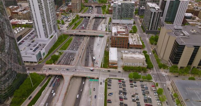Hundreds of cars on the roads and parking lots of amazing Chicago. Wide multi-lane road crossed by bridges of skyways. Top view.