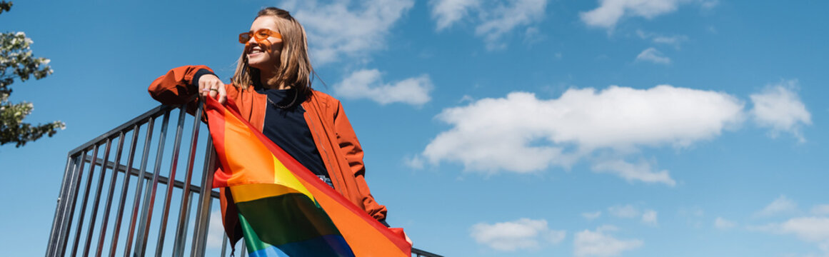 Happy Woman In Trendy Sunglasses Holding Lgbt Pride Flag Outdoors, Banner.