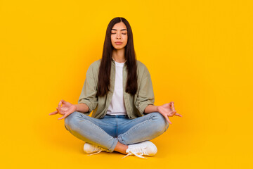 Full body photo of focused pretty person sit floor arms fingers meditate isolated on yellow color background