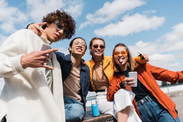 joyful multiethnic friends showing rock and victory signs while having fun outdoors.