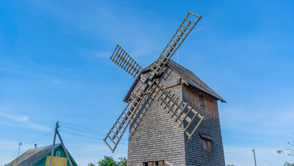 Vintage wooden windmill with cycling track on blue sky background. Historical farm house windmill. - obrazy, fototapety, plakaty