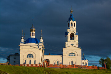 Obraz premium an old Orthodox church on the river bank.sunset sun and black clouds.