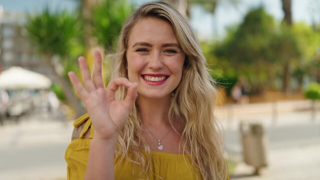 Young woman smiling confident doing ok sign at street