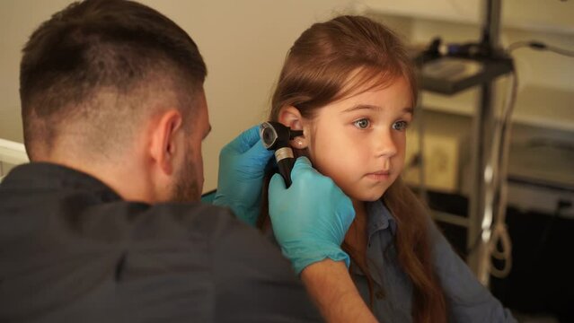 4k video ENT doctor with otoscope. Otoscopy. Pediatrician otolaryngologist looks through otoscope the ears of child. Otoscopy. Treatment ear pain.