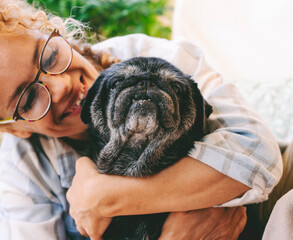 Cheerful woman hugging black old dog with love and freindship. Animal pug best friend forever....
