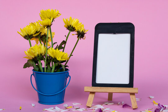 Note paper with frame and and flowers in blue bucket on pink background.