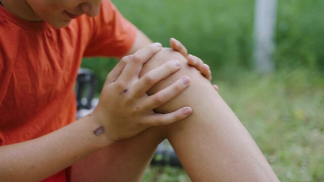 Wound on the knee. Pain from the received blow. The boy cries because of the fall. Accident with a bicycle. An accident in the park. The child cries because his leg hurts. Pity for an injured child.