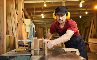 Senior carpenter in uniform works on a woodworking machine at the carpentry manufacturing